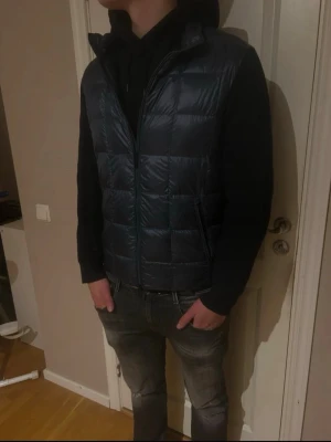 Mörkblå cardigan från Massimo Dutti - Säljer en stilren mörkblå cardigan från massimo dutti. Perfekt att slänga över en hoodie för en chill look. Materialet är syntet och dun, vilket gör den både lätt och varm.