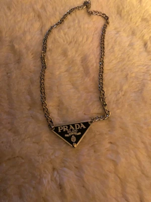 Prada Halsband  - Säljer ett Prada-halsband! ✨ Elegant och stilrent, perfekt för att piffa upp vilken outfit som helst. Ett riktigt blickfång som ger en lyxig touch. 💎💖