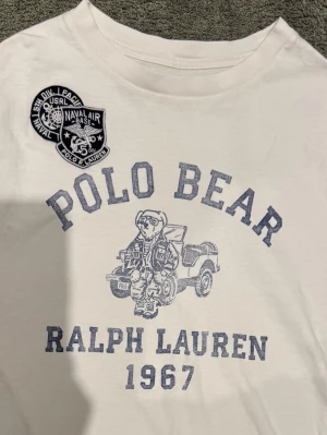 Polo Bear T-Shirt - Säljer en asfet T-shirt från Polo Ralph Lauren från deras ”Polo Bear” kollektion. Den har tryck och patches på framsidan och tryck på baksidan. Grymt skick utan defekter vad jag kan se. Självklart äkta. Storlek L/14-16 barn, passar XS