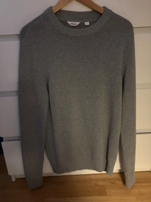 Grå stickad tröja från Dobber - En enkel och stilren grå stickad tröja från Dobber i storlek S. Tröjan har rund halsringning, ribbade muddar vid ärmslut och nederkant samt lång ärm. Perfekt för lager på lager under kyliga dagar. Aldrig använd!!!