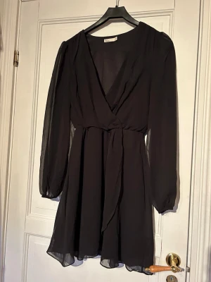 Svart omlottklänning - Säljer en svart kort omlottklänning från Nelly! Endast använd en gång, väldigt fint skick! 