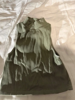 Grön polotopp🌴🥝 - Säljer en ribbad polotopp i en mjuk, ljusgrön färg. Toppen är ärmlös och har en lite högre krage som ger en cool vibe. Materialet är stretchigt och bekvämt, perfekt för att styla med jeans eller kjol. Passformen är croppad och toppen har en snygg struktur.🌴🌟✨