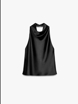 Svart halterneck topp i satin - Säljer en svart halterneck topp i glansigt satinmaterial. Toppen är ärmlös och har öppen rygg, vilket ger en snygg och modern look. Perfekt att styla med jeans eller kjol för en trendig outfit.