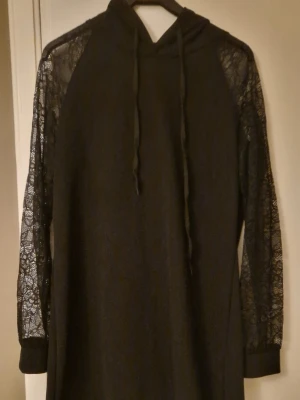 Lång hoodieklänning - Svart lång hoodie/klänning i mjukt, stretchigt material med spetsärmar, riktigt cool! Från Shein i stl XL. Kolla gärna in mina andra annonser! 