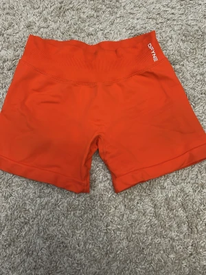  träningsshorts från DFYNE - Säljer ett par röda träningsshorts från DFYNE med hög midja och ribbad linning. Impact shorts. 