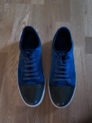 Blå sneakers från Lanvin  - Äkta Lanvin cap-toe Blå mocka + olivgröna lacktår (sällsynt combo) UK 7 ≈ EU 41 (passar 41,5–42,) Liten repa i lacket ena tån + hål på insidan. Övrigt toppskick. Ingen box/dustbag → 100 % äkta, nypris ~5 000 kr