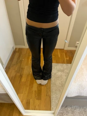 Svarta bootcut skinnbyxor från Bershka - Säljer ett par svarta bootcut skinnbyxkor från Bershka. Byxorna dragkedja fram och en snygg, glansig finish. Passformen är normal och de har en stilren look med fickdetalj bak. Endast använda 2-3 gånger💖
