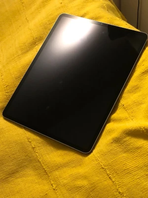 iPad Pro 2022 12.9 128GB - Snygg Apple iPad Pro med stor skärm och dubbla bakre kameror. Plattan ser ut att vara i mycket gott skick utan synliga repor eller skador. Perfekt för arbete, studier eller underhållning. Elegant design och kraftfull prestanda.