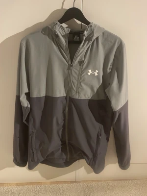 Under armor windbreaker jacka  - Jag säljer en grå under armour windbreaker jacka och är i mycket bra skick. Säljer för att den är för liten på mig. Pris kan diskuteras 