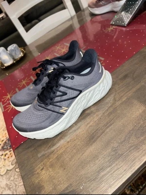 New Balance Fresh Foam X sneakers - Snygga New Balance Fresh Foam X sneakers i mörkgrått med vit, mönstrad sula. Ovandelen är i mesh och syntet med svarta snören och diskreta detaljer i guld. Skorna har rund tå och platt sula med unik struktur för extra komfort.