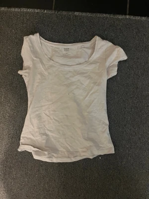Vit t-shirt från 157 - En enkel vit t-shirt från 157 med rund hals och korta ärmar. Tillverkad i mjuk bomull som känns skön mot huden. Perfekt för dig som gillar en clean och basic stil. Passformen är normal och t-shirten har en klassisk look.