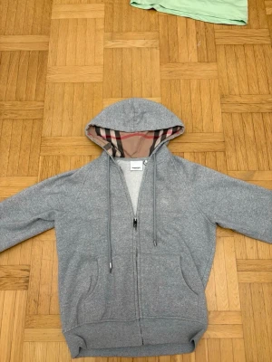 Grå burberry zip hoodie -  Grå Burberry zip – äkta Säljer en grå Burberry zip i storlek XS. Den är 100 % äkta och i bra skick. Klassisk och stilren modell som passar perfekt till vardags.  Snabbaffär prioriteras  hör av dig vid intresse!