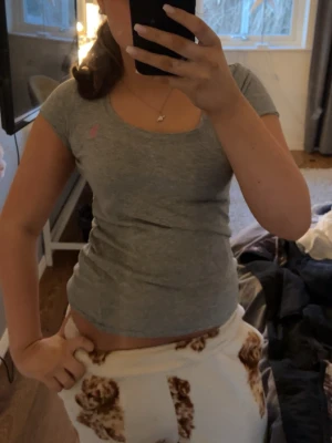 Grå tight t-shirt med kort ärm - Säljer en enkel och stilren grå t-shirt med tight passform och korta ärmar. Toppen har rund halsringning och är gjord i mjukt bomullsmaterial. Perfekt till jeans eller kjol för en avslappnad look.