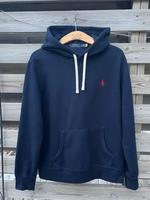 Marinblå Ralph Lauren Hoodie - Supersnygg Ralph Lauren Hoodie. Storlek M, passar som en Större S eller M. Väldigt fint skick, otroligt mjuk och skön Hoodie. Kan behöva tvättas efter köp då den inte använts på länge och legat i en garderob. Hör gärna av er vid funderingar🙌 Perfekt för vinterkylan☃️🔥