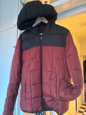 Svart och vinröd pufferjacka Primark - Säljer en pufferjacka från Primark i storlek L. Jackan är vinröd med svart axelparti och huva, har dragkedja framtill och två fickor. Perfekt för kalla dagar med sin quiltade design och sköna passform. I princip oanvänd. Large men ganska liten i storleken.