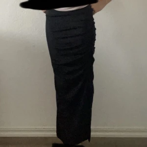 Svart ribbad långkjol med slits och rynk - Säljer en svart långkjol med snygga rynkade detaljer längs sidorna och en hög slits som ger kjolen extra edge. Kjolen har en tight passform och är gjord i ett mjukt, stretchigt material som sitter skönt mot kroppen.  | pris kan diskuteras | 💓