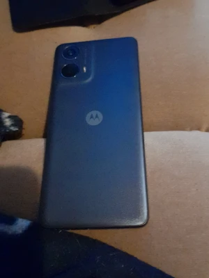 Motorola smartphone - Motorola smartphone i blå färg med dubbla bakre kameror. Enheten ser ut att vara i gott skick utan synliga repor eller skador. Levereras med ett praktiskt plånboksfodral. Perfekt för dig som söker en pålitlig Android-telefon till ett bra pris.