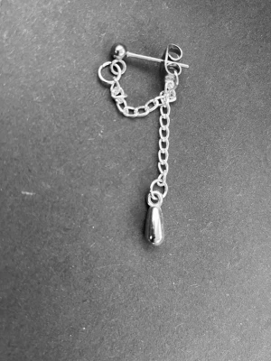 By prisförslag- 1 st Silverfärgad kedjeörhänge med droppe - Snyggt örhänge i silverfärgad metall med kedjedetalj och en droppformad hängande berlock. Designen är minimalistisk men ändå edgy, perfekt för dig som gillar att sticka ut med detaljer. Passar till både enkel och mer statement stil.