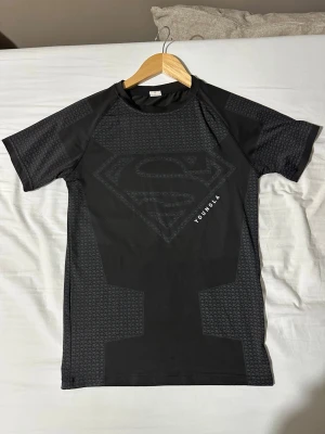 Svart Superman compression från YoungLA - Hejsan säljer den populära youngla compression shirt. Kövligt snygg och passar väldigt bra för gym. Passar S bra och men om man bär storlek M blir det utmärkt 