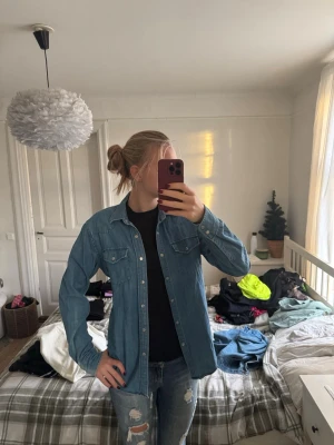 Jeansjacka från Emmett i medium - Säljer en klassisk blå jeansjacka från Emmett i storlek medium. Jackan har raka linjer, två bröstfickor med knappar och silverfärgade knappar framtill. Perfekt att slänga över en t-shirt för en chill look.
