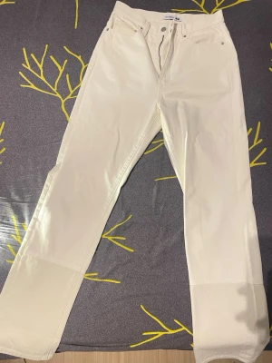 JW Anderson x Uniqlo vita raka jeans - W27 L32.    Snygga vita jeans från JW Anderson x Uniqlo med rak passform och klassisk femficksdesign. Byxorna har normal midja och är tillverkade i mjuk bomull. Perfekta för dig som gillar minimalistisk stil och vill ha ett fräscht tillskott i garderoben. 