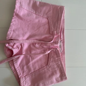 Rosa shorts från Mango med snörning - Säljer ett par ljusrosa shorts från Mango i bomull. Modellen har snörning i midjan, två framfickor och klassisk passform. Perfekta för varma dagar och riktigt snygga till en enkel t-shirt eller linne.
