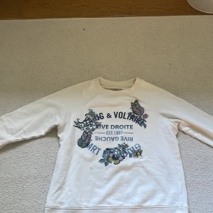 INTRESSEKOLL! Zadig tröja  - Vit sweatshirt med tryck och broderade detaljer från Zadig & Voltaire. Framsidan har text, blommor, fjärilar och bin i färgglada nyanser. Rund hals och långärmad modell i mjuk bomull. Perfekt för dig som gillar coola prints och snygga broderier. PRISET KAN DISKUTERAS