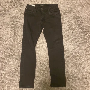 Svarta Jack & Jones jeans 32/30 - Svarta jeans med skinny fit och klassisk femficksdesign. Byxorna har normal midja och smala ben, perfekta för en clean och stilren look. Tillverkade i stretchigt jeanstyg för extra komfort.