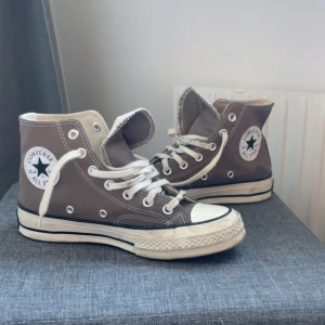 Bruna Converse All Star high-tops - Säljer ett par klassiska Converse All Star high-tops i brun canvas med vita snören och gummisula. Skorna har rund tå, vita detaljer och den ikoniska loggan på sidan. Använda några få gånger💗