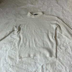 Vit stickad tröja från 157 XS - Säljer en vit stickad tröja från 157 i storlek XS. Tröjan har en högre ribbad krage och långa ärmar, samt breda ribbade muddar vid nederkant och ärmslut. Perfekt för dig som gillar enkel och clean stil med lite oversized känsla.