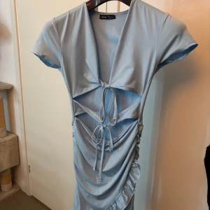 Ljusblå kortklänning från Shein - Supersnygg ljusblå klänning från Shein med coola snörningsdetaljer framtill och rynkade sidor. Klänningen har korta ärmar, v-ringad hals och en tight passform som framhäver figuren. 