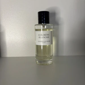 Cologne Blanche från Christian Dior sampel - Exklusiv parfymflaska från Christian Dior, Cologne Blanche. Flaskan är cylindrisk i genomskinligt glas med svart lock och vit etikett. Innehållet är ljust gult. En stilren och lyxig doft för dig som gillar klassiska parfymer.