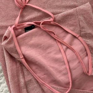 Glittrig rosa kortklänning från Shein - Supersöt rosa kortklänning från Shein med tunna axelband och glittrigt tyg. Klänningen har en tight passform och är ärmlös, perfekt för dig som vill sticka ut. Snygg drapering vid bysten och skimrande material som fångar ljuset.