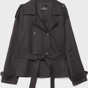 Svart kort trenchcoat från Stradivarius - Kort svart trenchcoat med bälte i midjan. Helt ny med prislapp på, slutsålt i M på hemsidan☝️