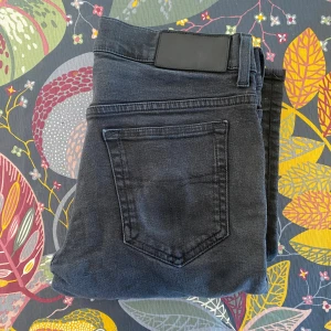 Svarta slim jeans Tiger of Sweden - Snygga svarta jeans från Tiger of Sweden i modellen slim. Jeansen har klassisk femficksdesign, raka bakfickor och smal passform hela vägen ner. Tillverkade i Italien och perfekta för dig som gillar stilrena och tajta jeans.