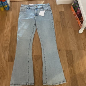 Ljusblå flare jeans low waist L/31 - Snygga ljusblå jeans från Never denim i modellen Low Flare. De har låg midja och utsvängda ben, vilket ger en retro och trendig vibe. Klassisk femficksdesign och tillverkade i mjukt jeanstyg. Perfekta för dig som gillar en avslappnad men cool stil. HELT NYA! Nypris: 599kr 