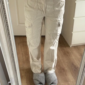 Beiga cargopants med raka ben - Säljer ett par beiga cargopants med raka ben och flera praktiska fickor på sidorna. 