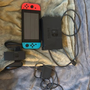 Nintendo switch i mycket bra skick  - Det här är ingen bok, utan en Nintendo Switch-spelkonsol med tillbehör. Perfekt för dig som vill spela både hemma och på språng! Inkluderar Joy-Con-kontroller, dockningsstation, handkontrollshållare och laddare. En grym spelupplevelse för unga och unga vuxna.