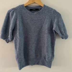 Ljusblå stickad tröja Vero Moda - Superfin ljusblå stickad tröja från Vero Moda med korta puffärmar och rund halsringning. Tröjan har ribbade muddar vid ärmslut och nederkant, vilket ger en snygg och bekväm passform. Perfekt för lager-på-lager under vår och höst.tröjan är lite noppig men fin