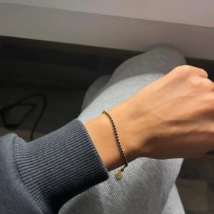 Svart strassarmband med gulddetalj - Använd få gånger. I rostfritt stål, tål vatten 