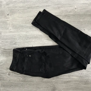 Svarta Replay Hyperflex jeans - Svarta jeans från Replay Hyperflex med klassisk femficksdesign och silverfärgade detaljer. Jeansen har en smal passform och stretchigt material som ger extra komfort. Snygga svarta sömmar och diskret Replay-logga vid fickan.