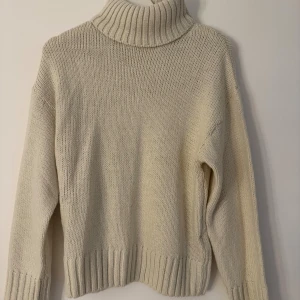 Beige polotröja från NA-KD XS - Beige polotröja från NA-KD i storlek XS. Tröjan är stickad med bred ribbad polokrage och muddar vid ärmslut och nederkant. 