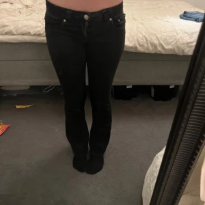 Svarta jeansbyxor från Gina Tricot - Svarta jeansbyxor från Gina Tricot med boot cut och snygga bakfickor med lock och silverknappar och normal passform