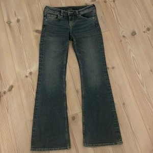 Blå bootcut jeans från H&M Divided - Snygga blå bootcut jeans från H&M. Jeansen har  låg midja och utsvängda ben.