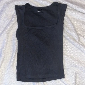 Mörkgrå linnetopp från Gina Tricot - En stilren mörkgrå linnetopp från Gina Tricot med fyrkantig ringning och breda axelband. 