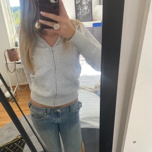 Ljusblå bootcut jeans från True Religion - Säljer ett par ljusblå jeans från True Religion med klassiska detaljer på bakfickorna och snygg bootcut-passform. Jeansen har låg midja och är tillverkade i mjukt denimtyg som sitter skönt. Perfekta för dig som gillar en avslappnad men trendig look.