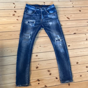 Frankie Morello Jeans - Ett par feta blåa Frankie Morello med snygga slitningar och detaljerade sömmar på bakfickorna. Jeansen har slim fit och passar till mycket. Klassisk femficksdesign och är tillverkade i bomull. Snyggt tvättade med många slitningar som sticker ut. Knappt använda och ser helt nya ut. Frågor? Skriv bara!