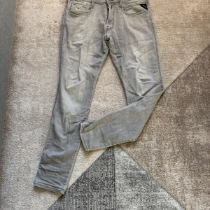 Replay Anbass grå slim jeans - Snygga grå jeans från Replay, modell Anbass med slim fit. Klassisk femficksdesign, dragkedjegylf och coola detaljer på bakfickorna, smal passform som sitter riktigt bra.