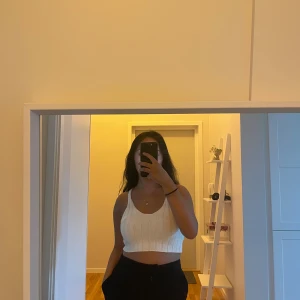 Vit ribbad croppad linnetopp - Säljer en vit croppad linnetopp med breda axelband och ribbad struktur. Toppen har en enkel och fräsch design som är perfekt för varma dagar. Passar dig som gillar en clean och stilren look med lite edge.