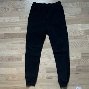 Svarta mjukisbyxor Jack & Jones XS - Svarta mjukisbyxor från Jack & Jones med elastisk midja och dragsko. Byxorna har ribbade muddar vid bensluten och är tillverkade i mjukt material som är skönt att ha på sig. Perfekta för chill eller träning. Köpta för 699 kr 